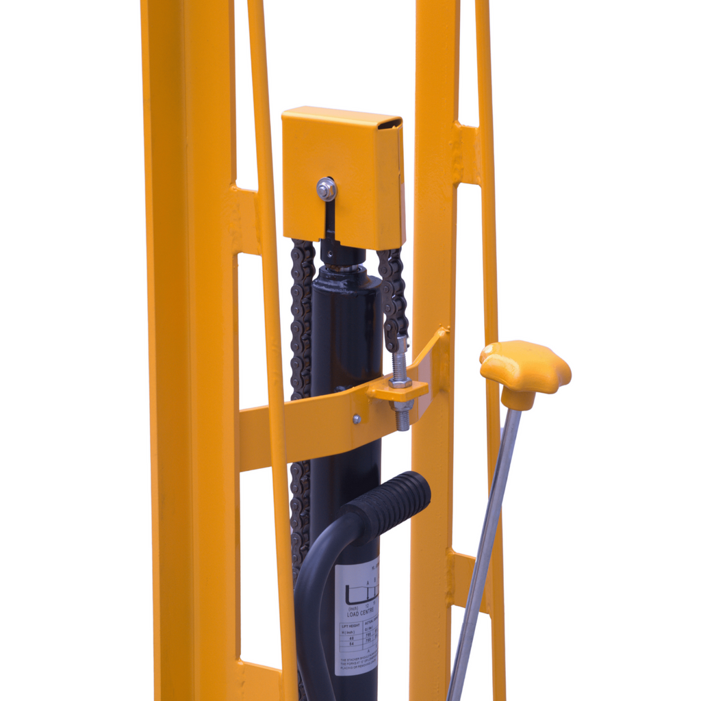 Close-up of a hydraulic lift with a yellow frame, chains, a control handle, and a pressure gauge, designed for lifting heavy loads.