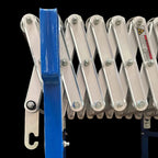 Close-up of a blue metal conveyor mechanism with bolts and warning label.