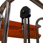 Close-up of a pulley system with a black attachment and metal chain, mounted on a shiny chrome structure against an orange background.