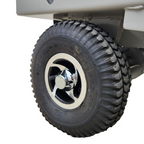 Close-up of a rugged black tire with a chrome rim, showcasing a detailed tread pattern and clear branding on the sidewall.