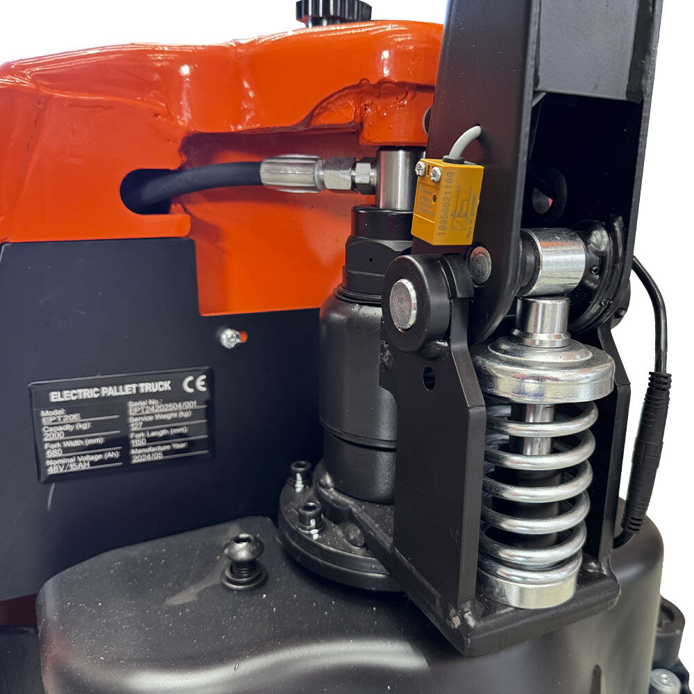 Close-up of an electric pallet truck's hydraulic system, showcasing the pump, spring, and control components in detail.