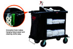 Black housekeeping trolley with 4 wheels, a side bin bag, cleaning supplies on top, and white cloths across two shelves.