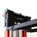 Close-up of a heavy-duty forklift attachment, showcasing a robust black steel design mounted on an orange forklift frame.