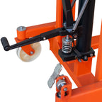 Close-up of an orange hydraulic lift mechanism with a manual foot pedal, spring, and caster wheel.
